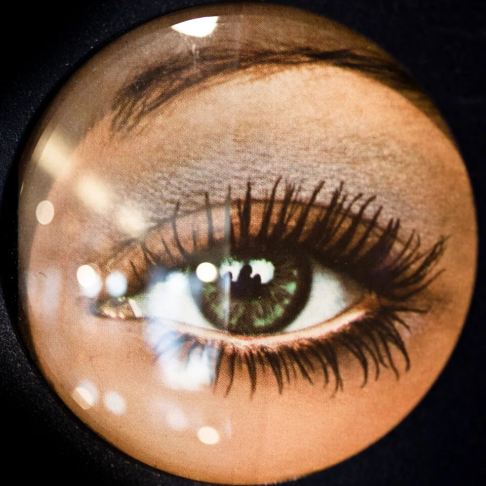Comparison of an ordinary lens and an antireflection-coated lens over the same image, with strong lamp reflections on the ordinary side and weak reflections on the coated side